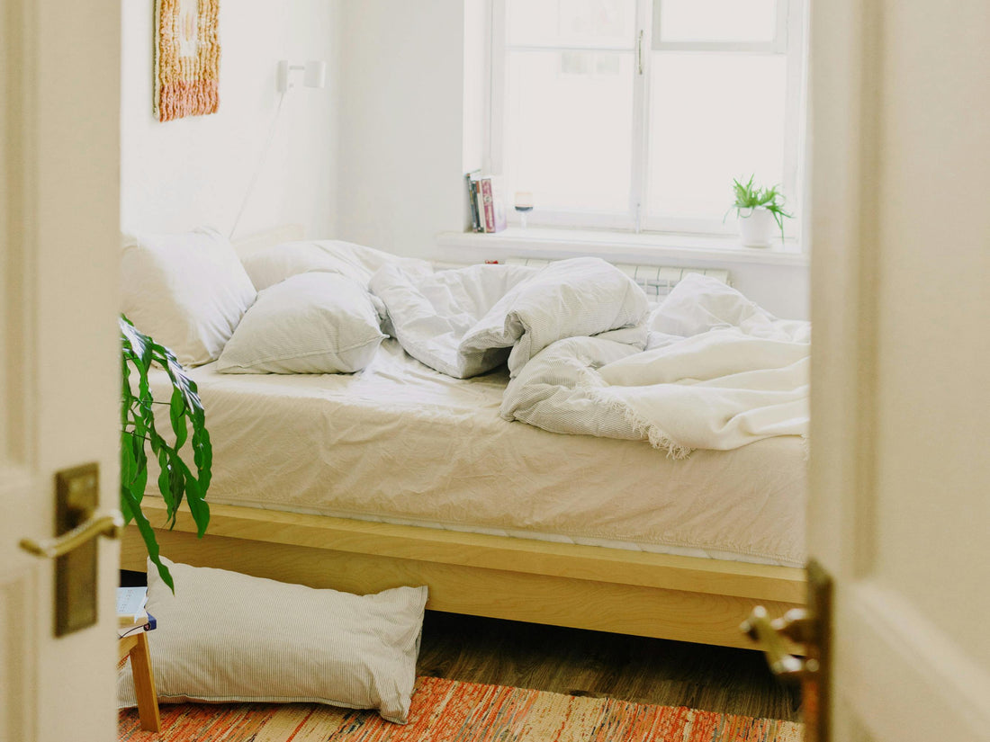 A light couch with a dark blue blanket with pillows and book scattered on it