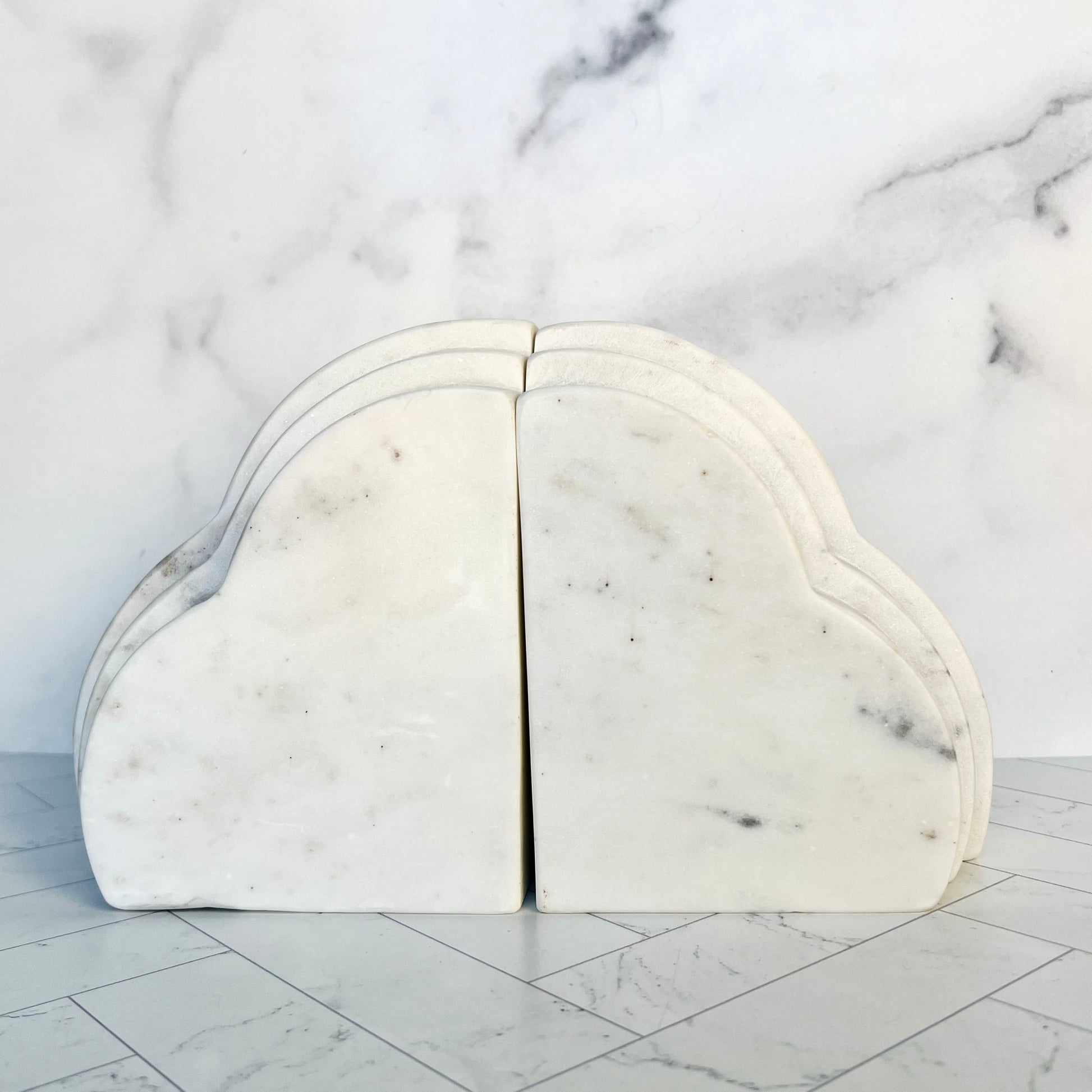 Two cloud white marble bookends pushed together against a white marble background