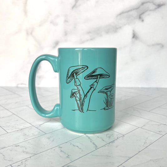 Turquoise mug with a handle with brown wild mushrooms printed on it