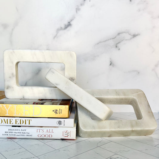 The White Marble Decor Chain cascading off a stack of white and gold books against a light background