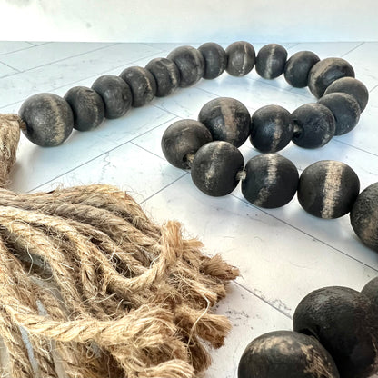 A black bead garland shown up close to see the detail of the beads and the jute tassels