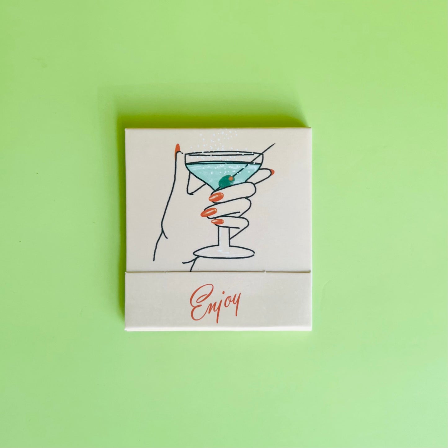 Martini matchbook front featuring a drawing of a hand holding a dirty martini