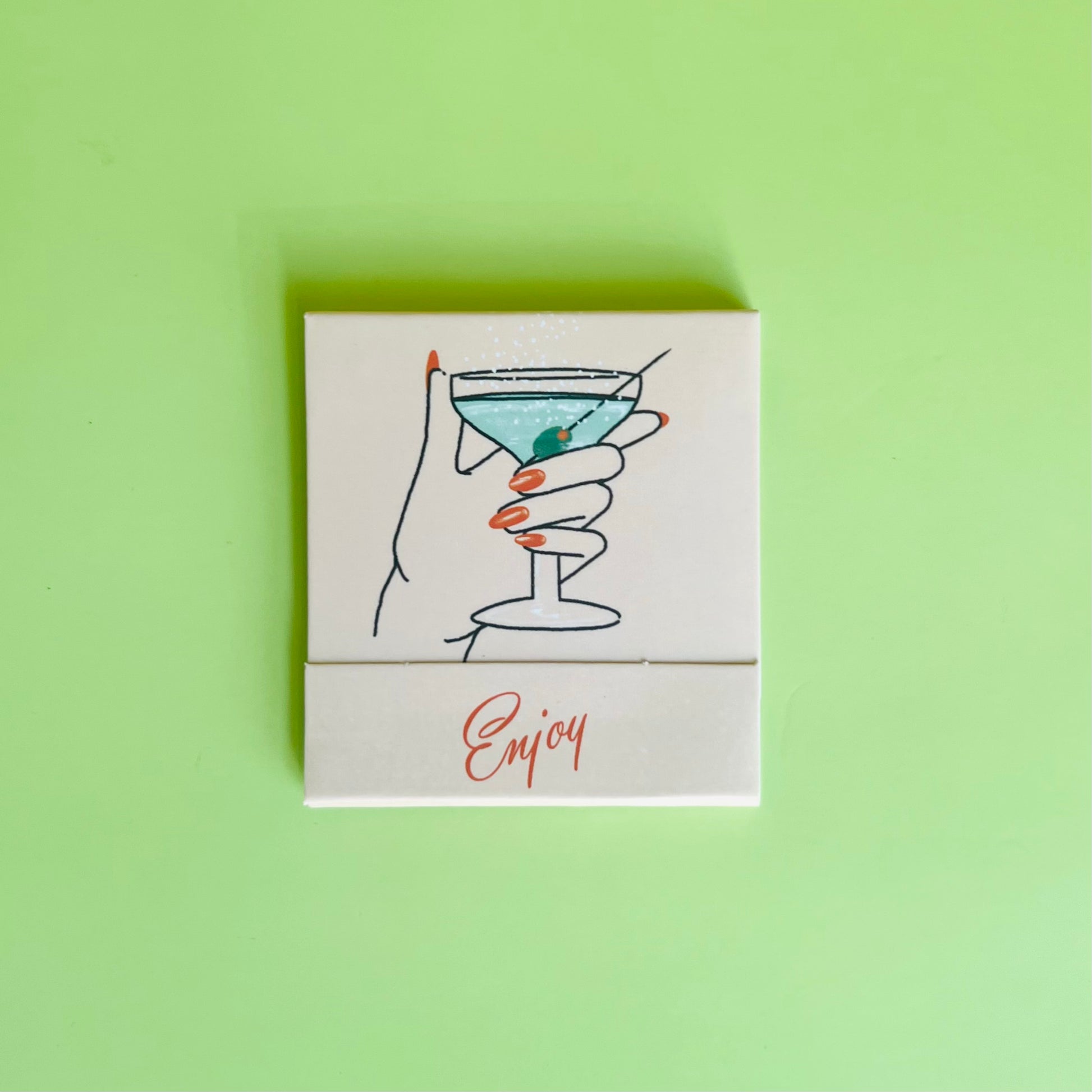 Martini matchbook front featuring a drawing of a hand holding a dirty martini