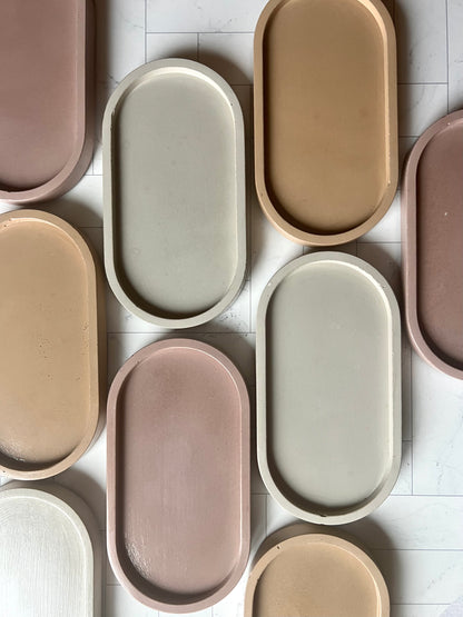 An array of the Oval Tray in alternating light gray, sand, and mauve