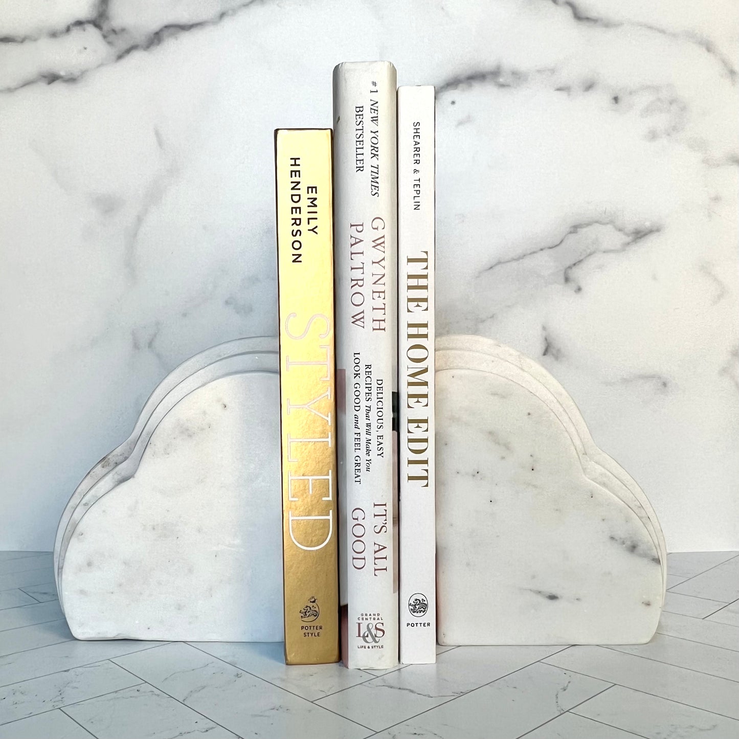 Two white marble bookends framing three books of gold and white color