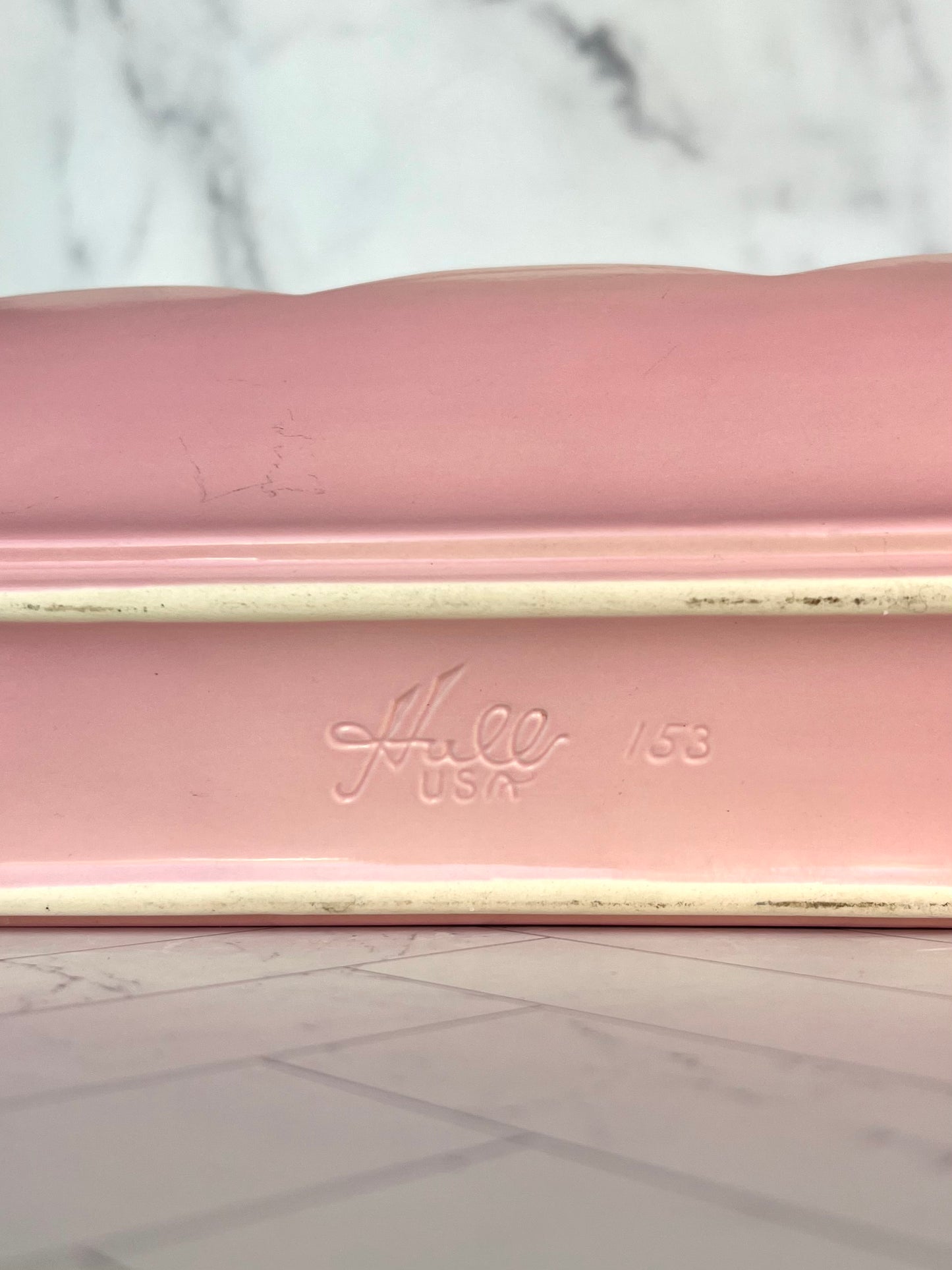 The bottom of a pink ceramic planter showing the name "Hull USA 153" stamped into it