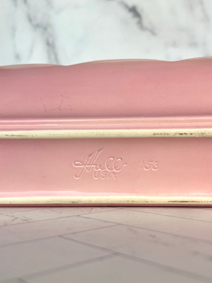 The bottom of a pink ceramic planter showing the name "Hull USA 153" stamped into it