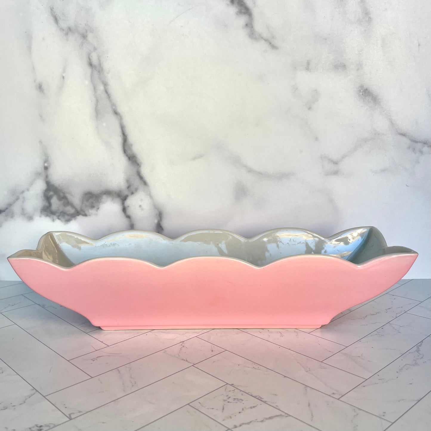 A pink, scalloped-edge dish on a white tiled surface