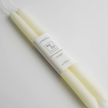 A set of natural white beeswax candles against a blank white surface