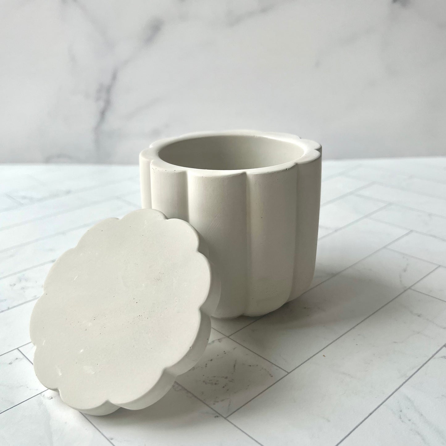 The Scallop Jar in Light Gray with the lid resting against it