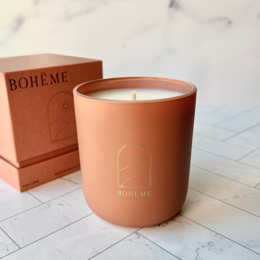 A terracotta-colored candle with a box in the background of the same color