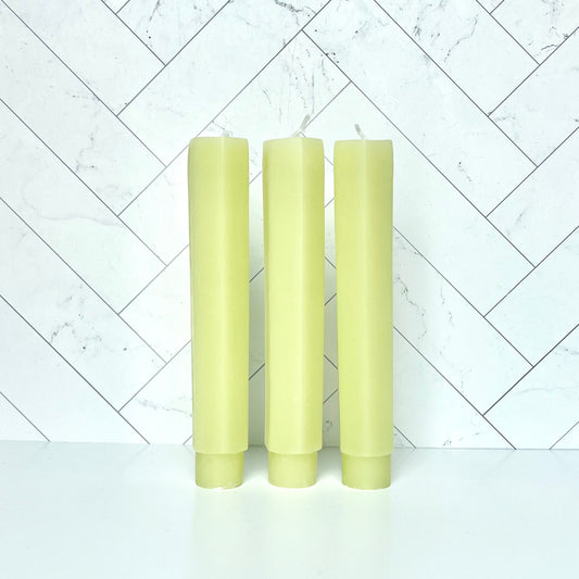 Three melon-colored taper candles standing in a row