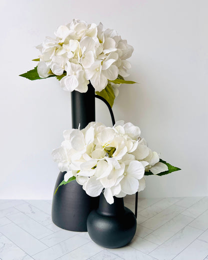 The Sleek Bud Vase and Sleek Metal Vase both filled with white flowers