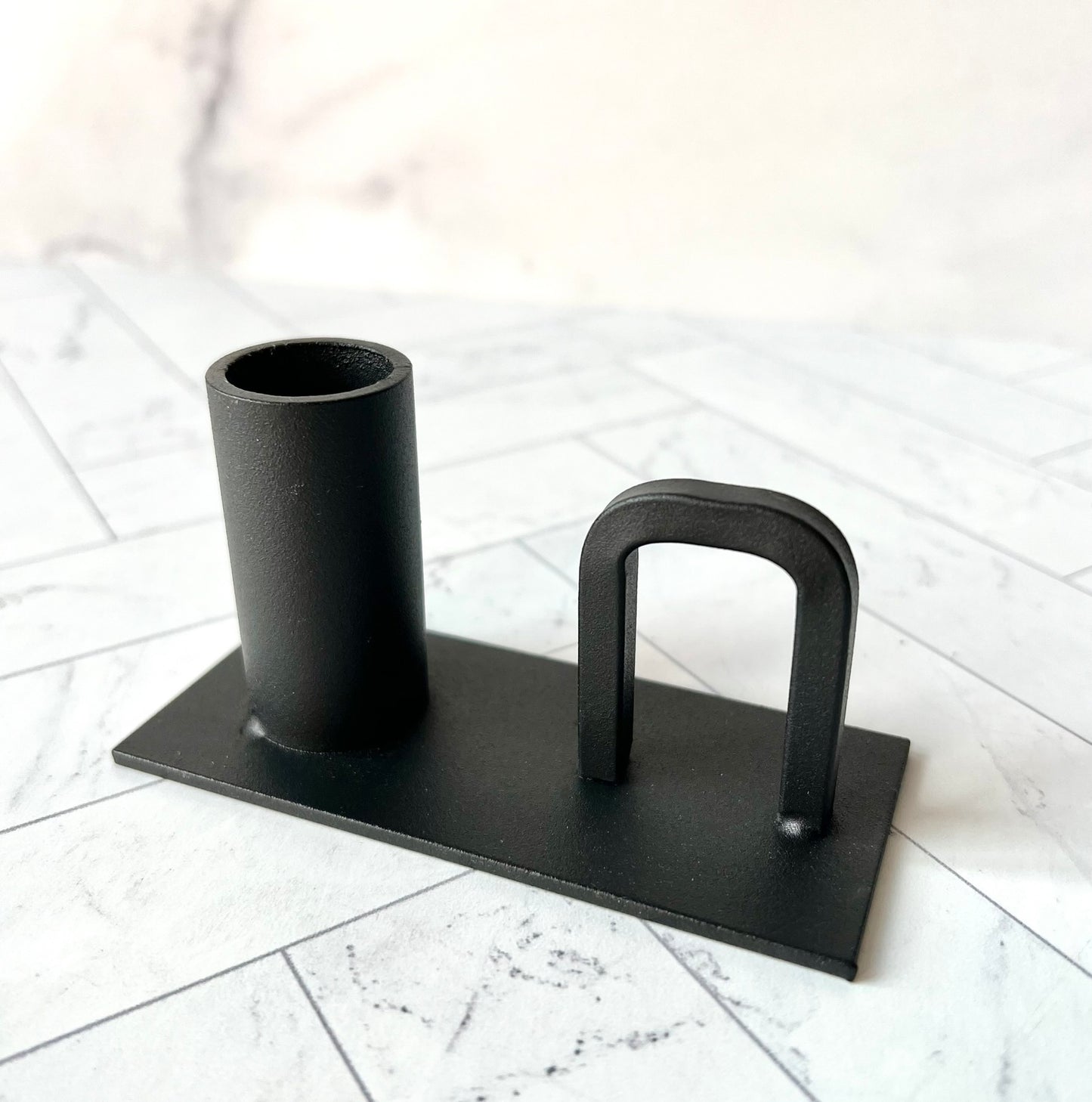 A black candlestick with a handle shown from an angle - The Offbeat Co.