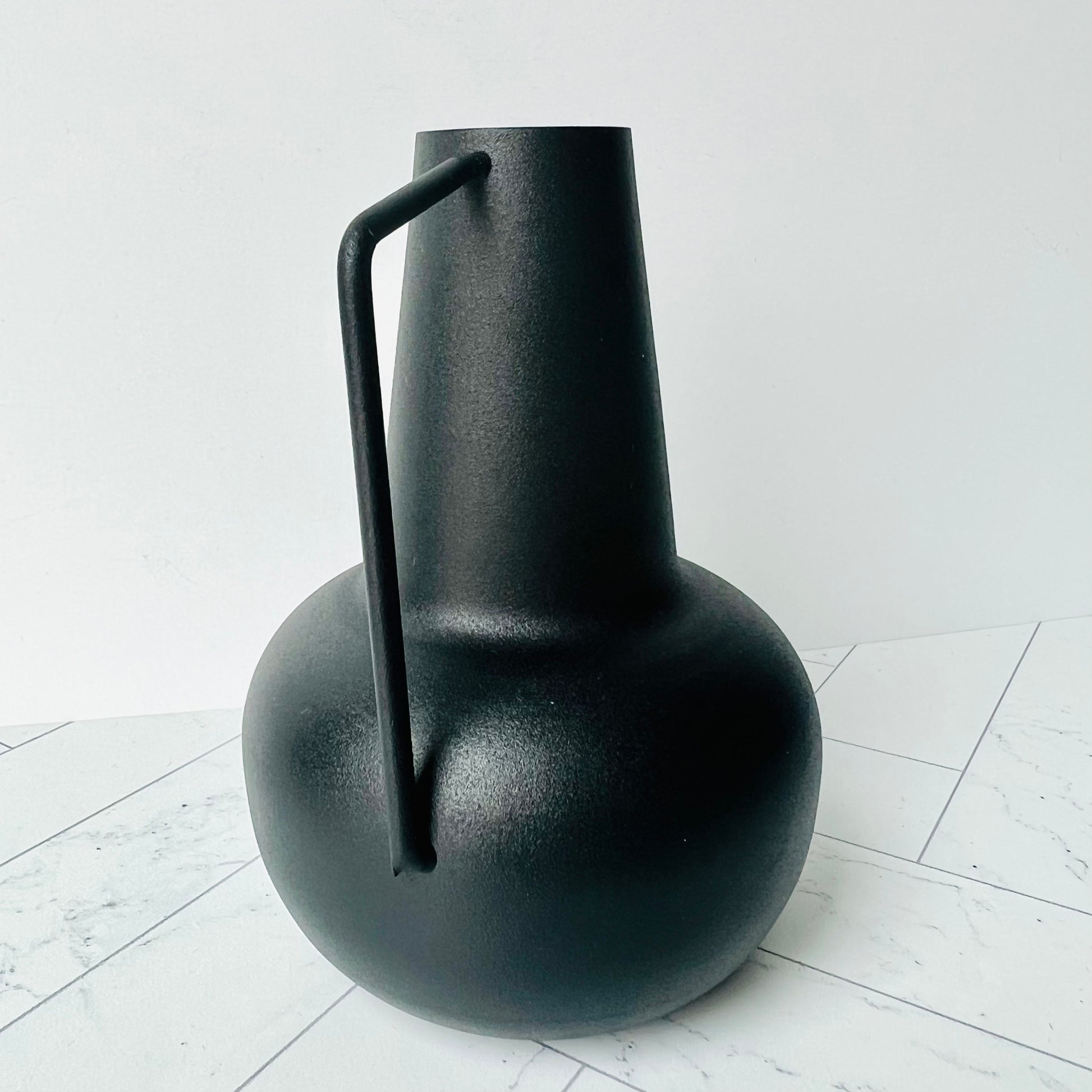 The Sleek Bud Vase on a light surface showing its handle and shape up close