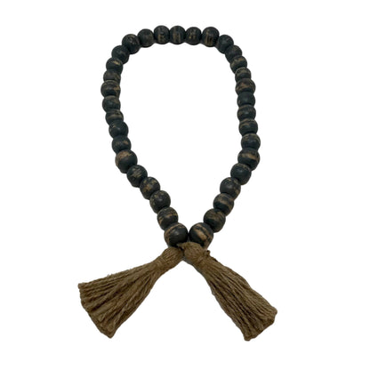 a black wood bead garland with brown jute tassels against a blank background 