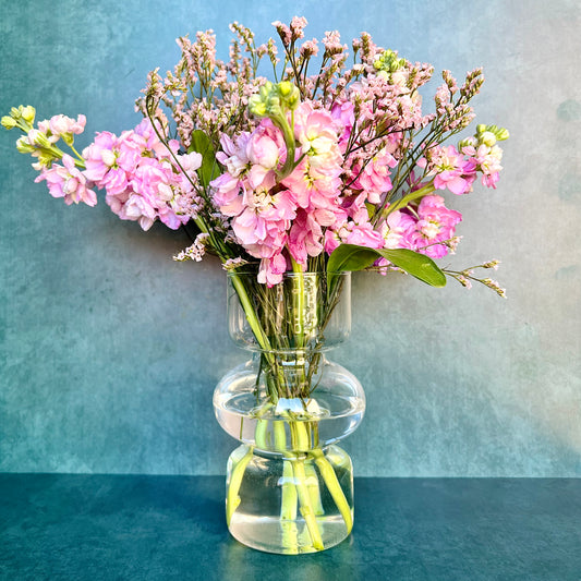 The Curvy Glass vase filled with a pink flower arrangement