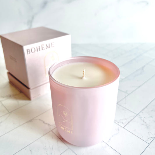 A pink candle shown at an angle with its pink box container behind