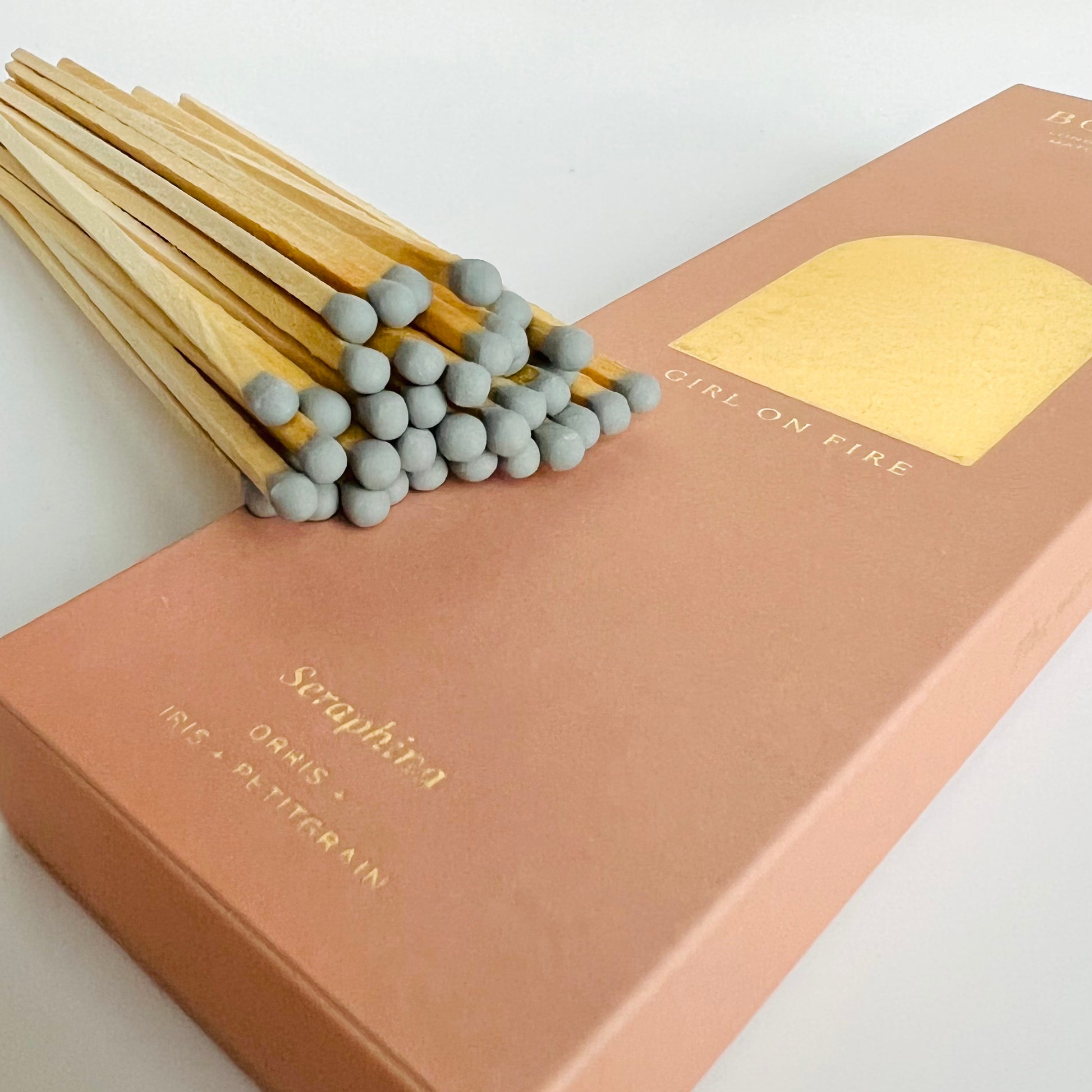 The tips of the Long Seraphina Scented Matches resting on the pink box with a gold emblem - The Offbeat Co.