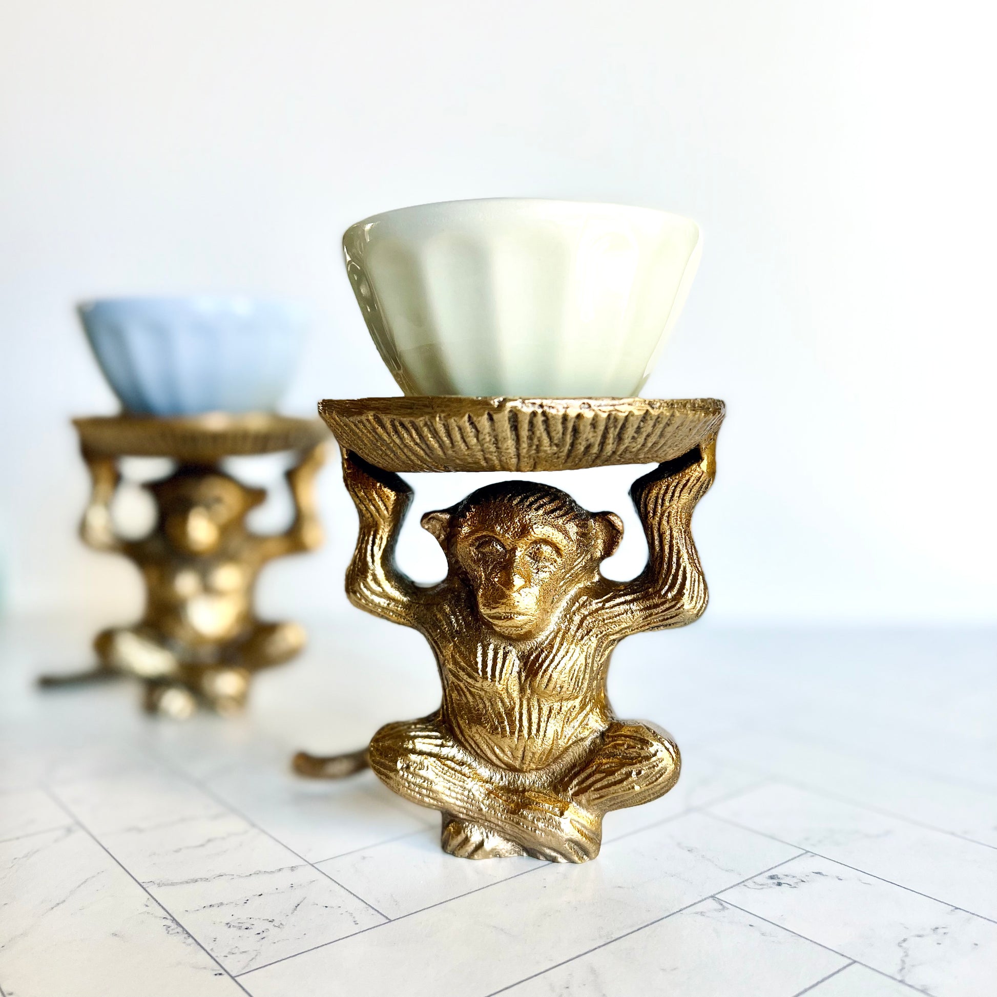 A brass monkey figurine with a second one in the background