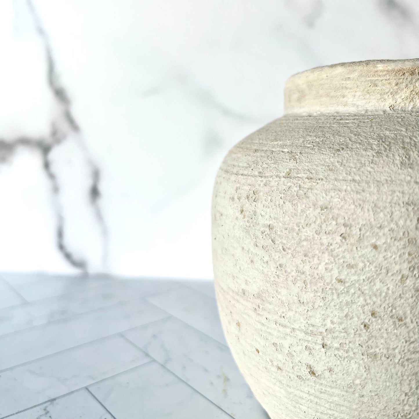 A close up of the right side of the Petite Concrete Vase showing its texture, striations running horizontally around it