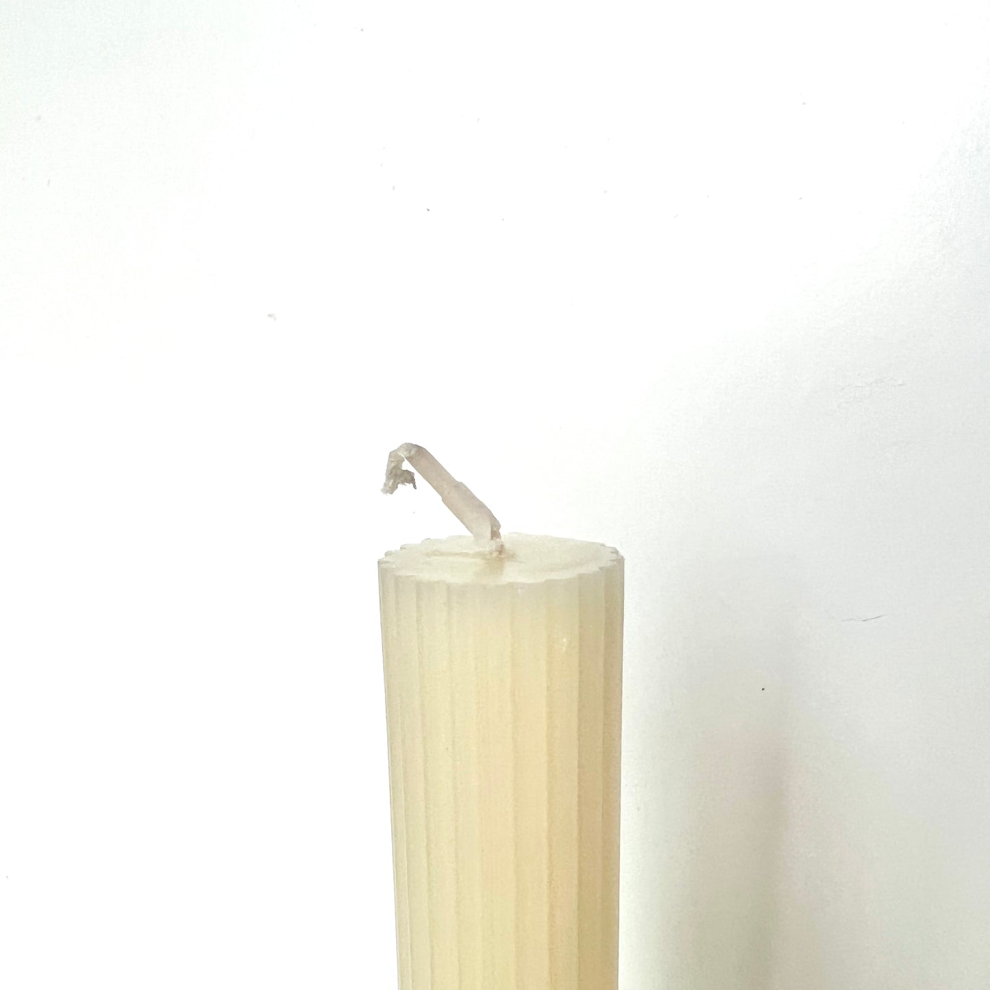 The top of a cream-colored taper candles showing its flat top against a white background