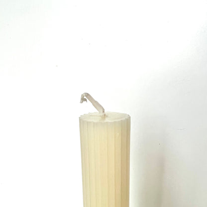 The top of a cream-colored taper candles showing its flat top against a white background