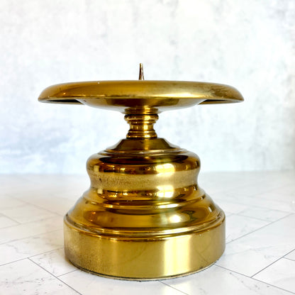 a large pillar candlestick made of brass on a light surface