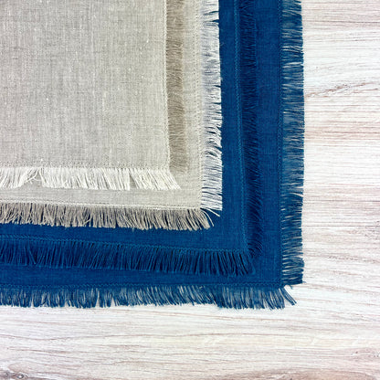 A stack of linen napkins, light beige on top of and dark blue underneath