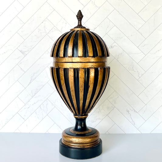 A black and gold decorative object in a somewhat of a teardrop balloon shape
