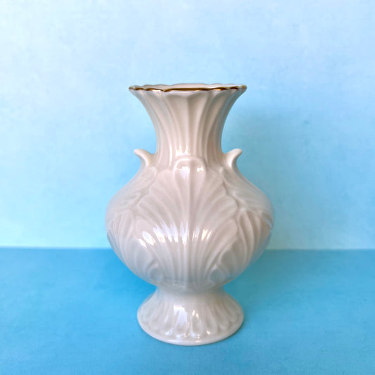 A small vintage bud vase against a blue background