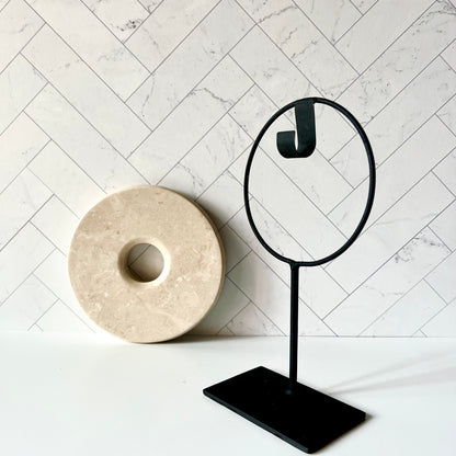 A beige marble disc sitting next to a black stand to show how the pieces separate