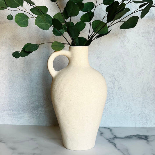 The Tulum White Vase filled with eucalyptus against a light background